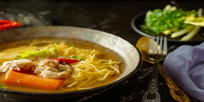 A bowl of soup with noodles and vegetables
Description automatically generated