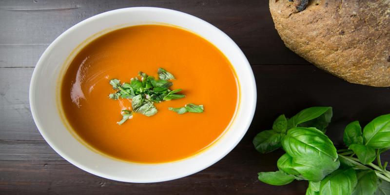 A bowl of soup with basil in it
Description automatically generated